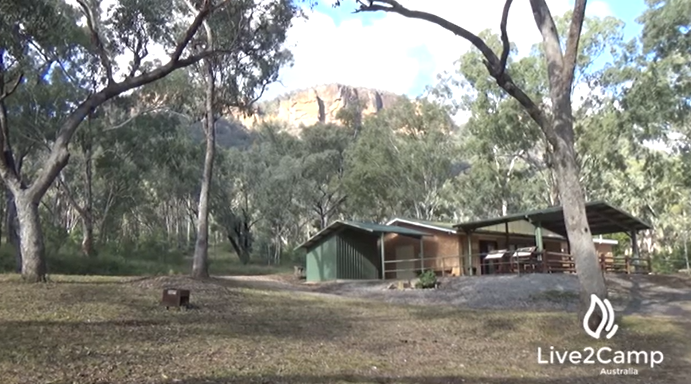 Glen Davis campground with community centre, sheltered sitting area and fireplace in foreground.