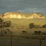 Sunrise rays shining on Pantoneys Crown, a flat-topped mesa located in the Capertee Valley, New South Wales, Australia.